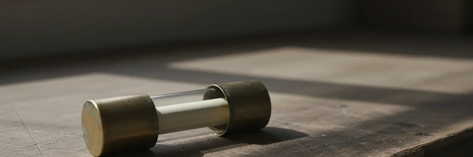 A brass pneumatic tube capsule opened in two halves, a rolled blank paper slip half out of it.